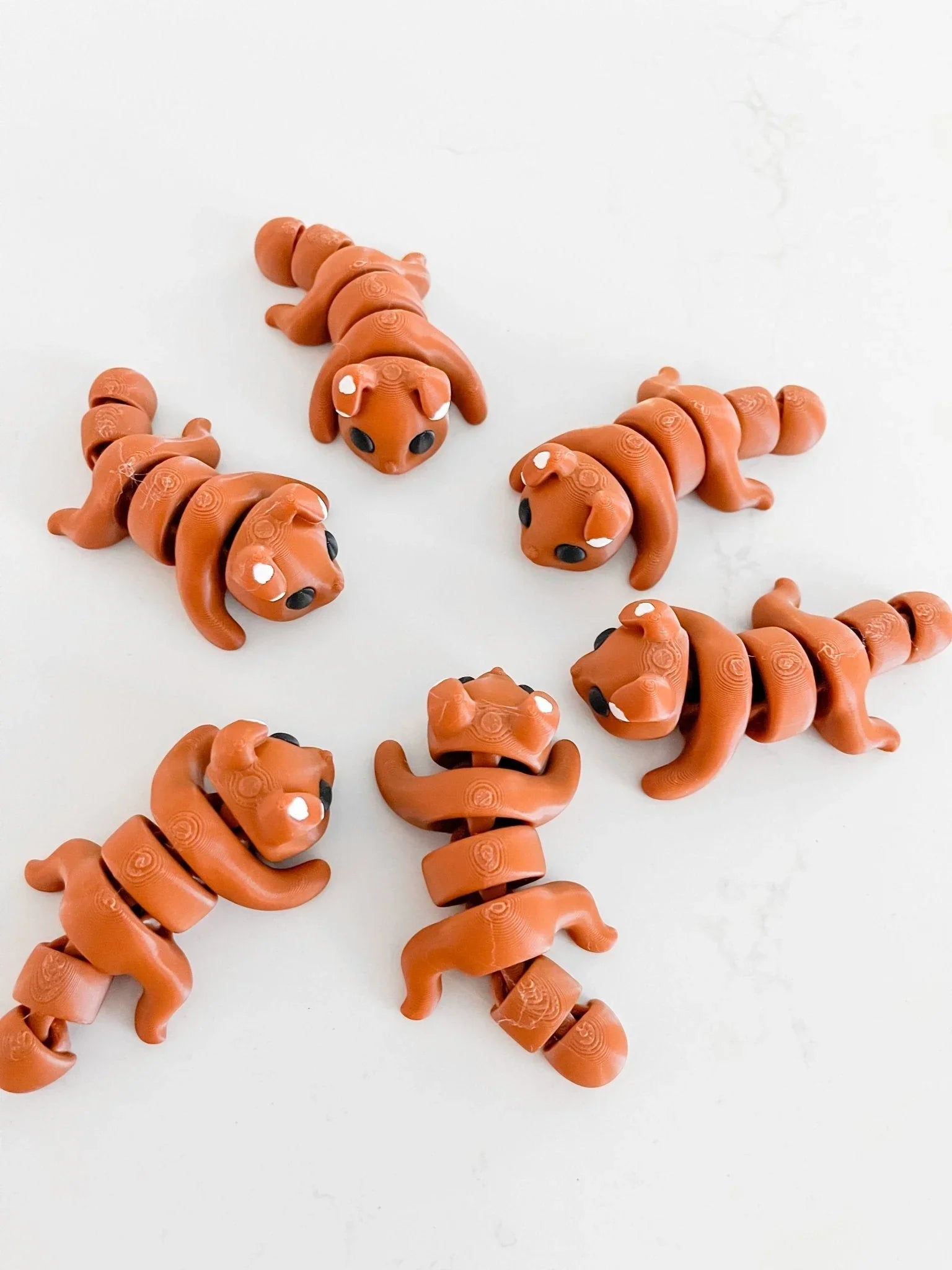 Artist-designed segmented dog fidget toys in terracotta color on a white background