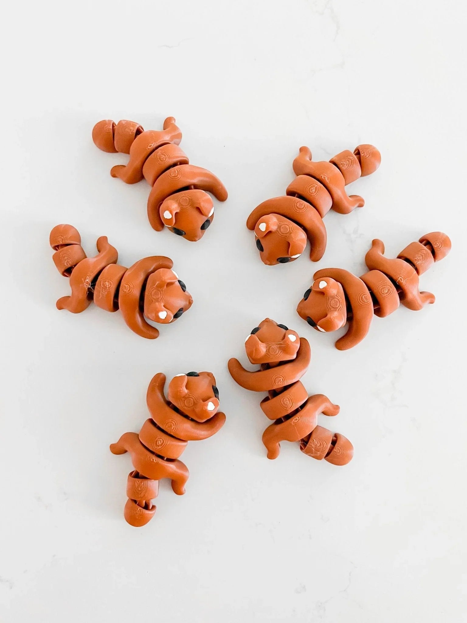 Artist-designed brown dog fidget toys arranged in a circle on a white background