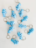 Blue baby narwhal keychain with white tusk, playful design on a white background from Qu!rk Boutique.