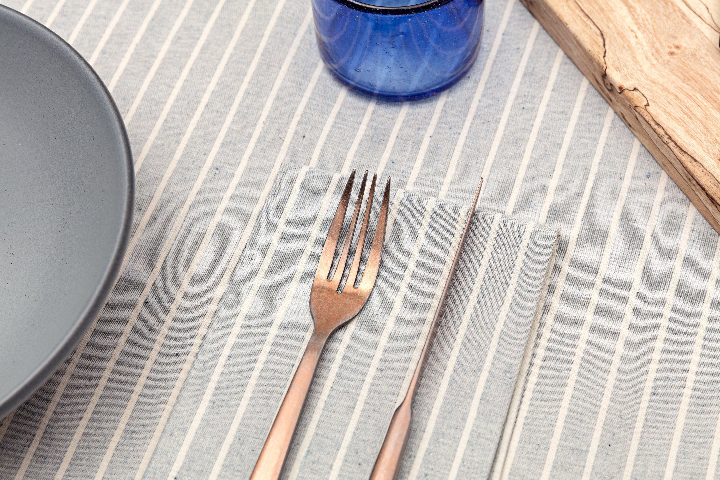 Striped placemat with fork, knife, blue glass, gray bowl, and wooden board, Qu!rk Boutique style
