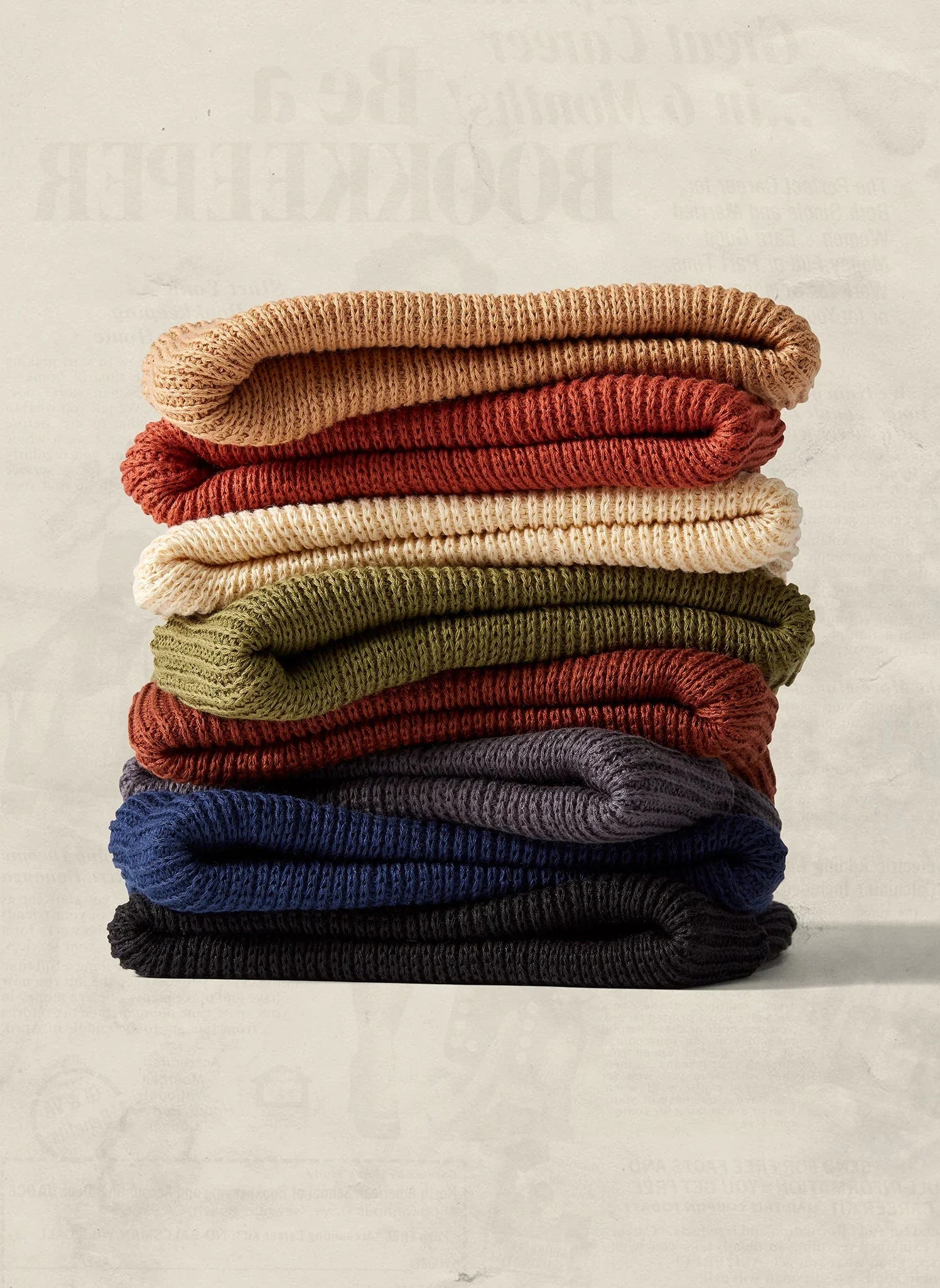 Stack of colorful knit beanies in earthy tones from Qu!rk Boutique, cozy winter accessories.
