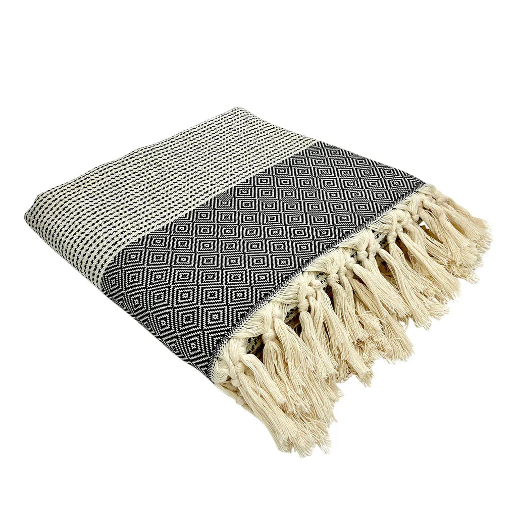 Black and white diamond pattern throw blanket with fringe, folded on white background