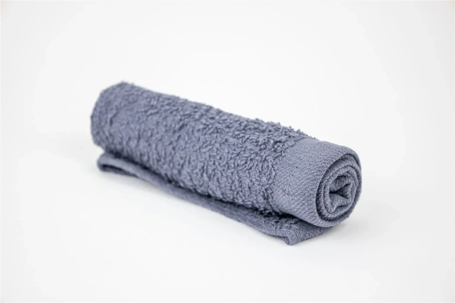 Rolled gray terry cloth towel on white background, soft cotton bath linen