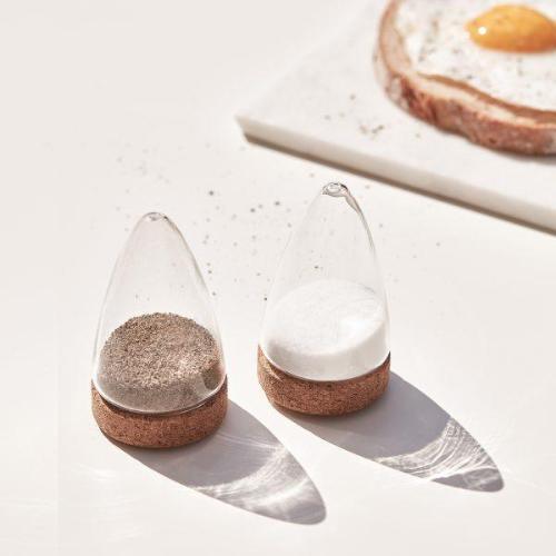 Minimalist glass salt and pepper shakers with cork bases beside a fried egg on toast