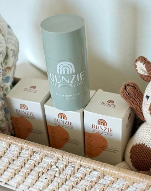 BUNZIE diaper rash cream and protectant boxes in woven basket, eco-friendly baby care scene.