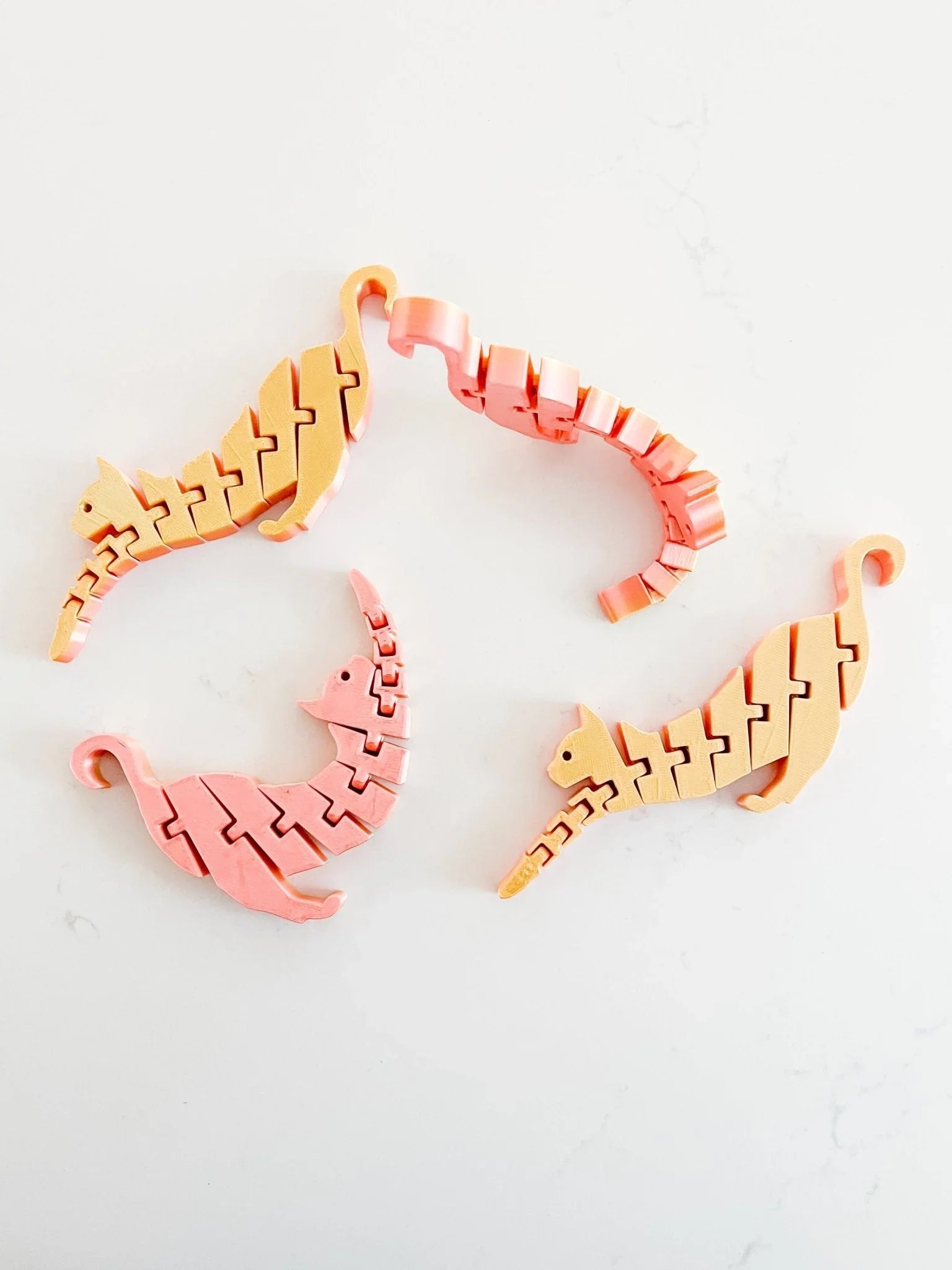Pastel pink and yellow cat-shaped fidget toys on white background, playful boutique gift