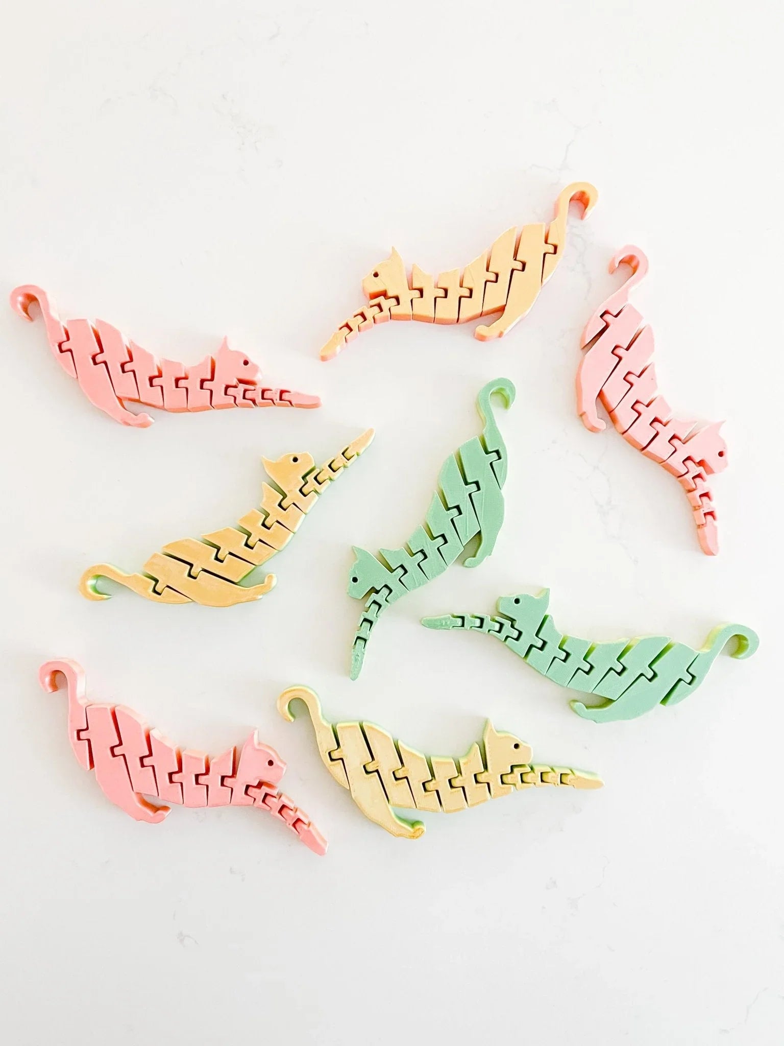 Pastel cat-shaped fidget toys arranged on a white background, playful artisan gift at Qu!rk Boutique.
