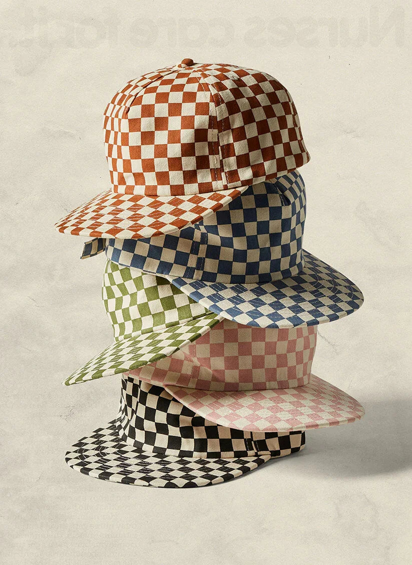 Stack of four checkerboard baseball caps in brown, blue, green, pink, and black at Qu!rk Boutique