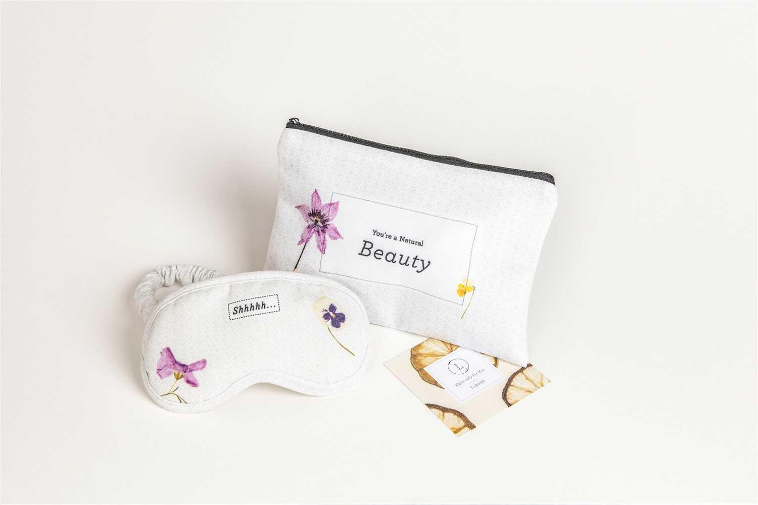 White cosmetic bag with floral design and 'You're a Natural Beauty' text beside matching eye mask with 'Shhhhh...' text