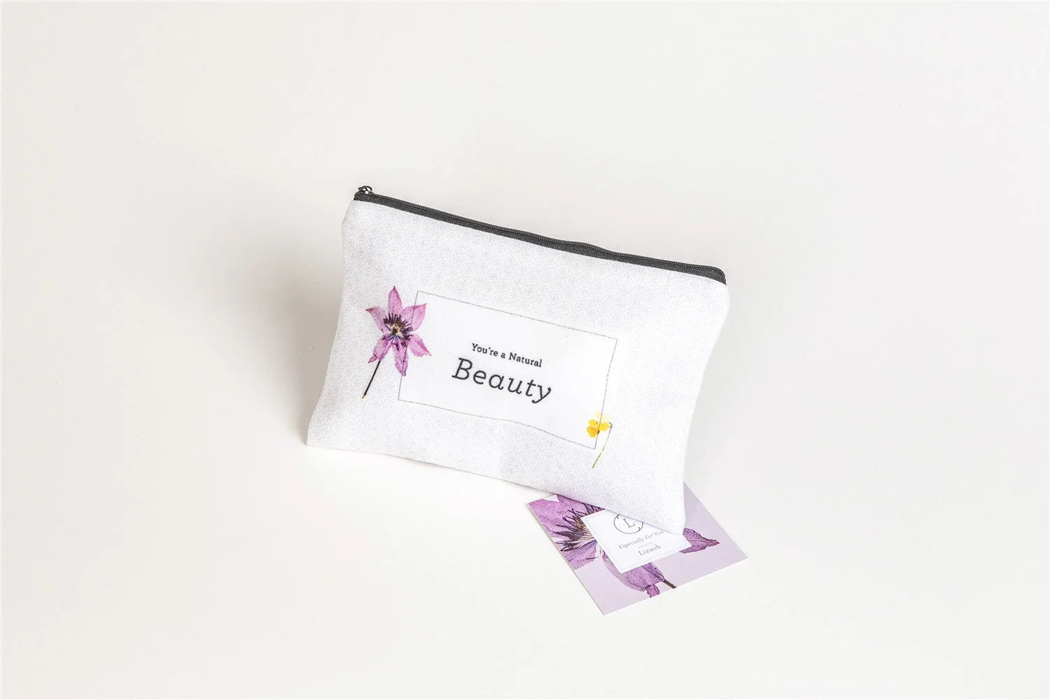White cosmetic bag with purple flower art and 'You're a Natural Beauty' text, Qu!rk Boutique gift