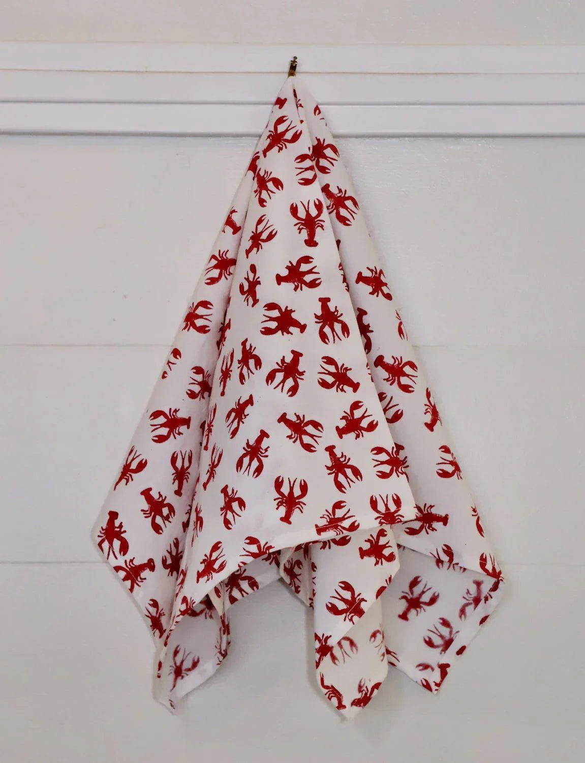 White cotton tea towel with red crawfish print, hanging on a white wall, Qu!rk Boutique gift