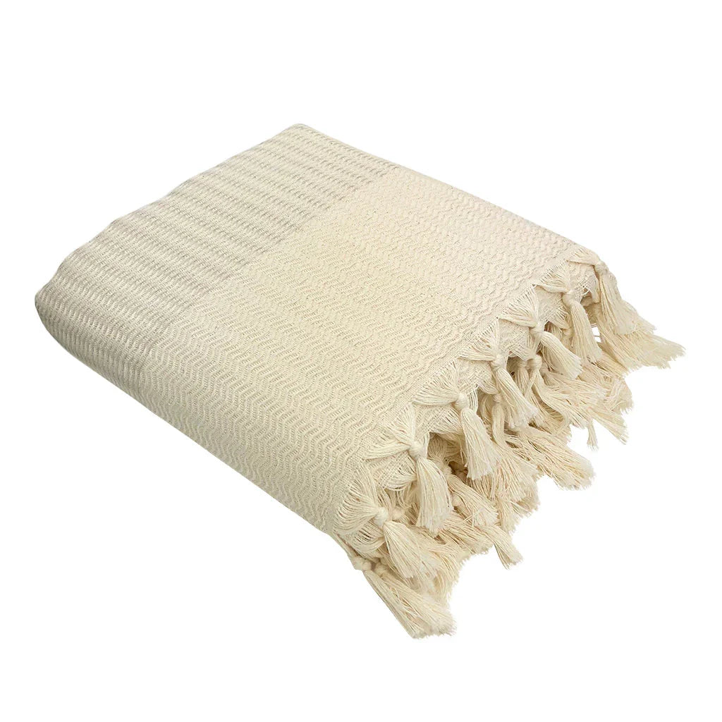 Cream Turkish throw blanket with fringe, folded, artist-designed home decor from Qu!rk Boutique.