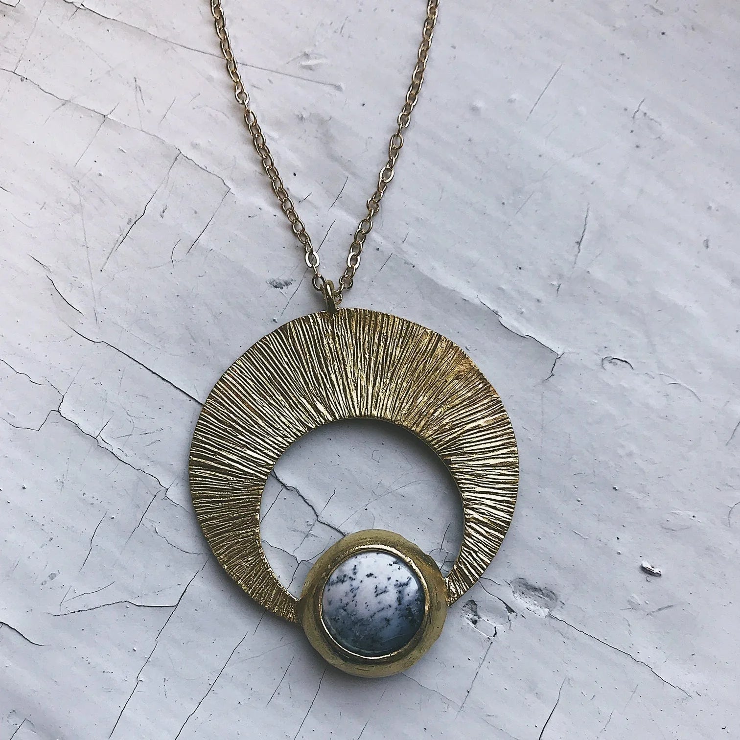 Artist-designed crescent pendant necklace with gold textured arc and marbled stone on chain