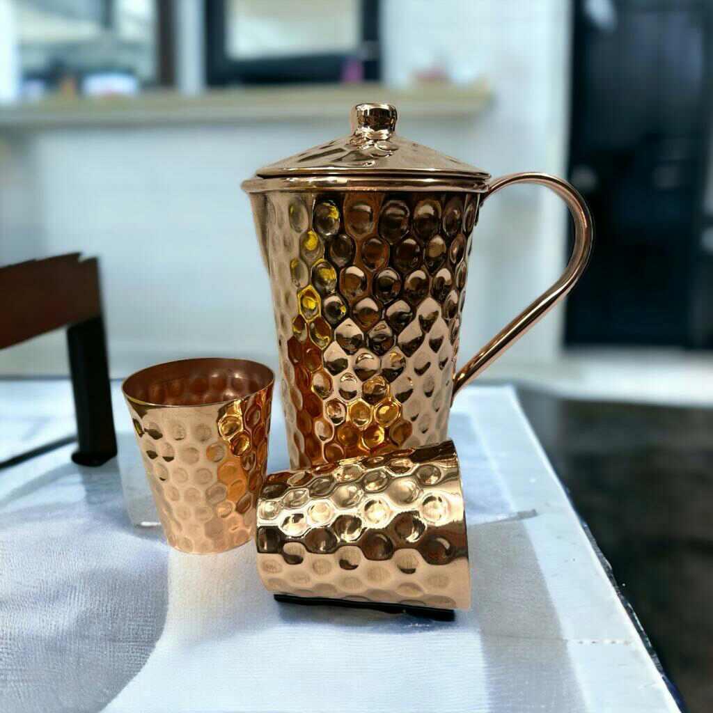 Hammered copper pitcher with lid and two cups on display at Qu!rk Boutique gift shop