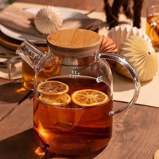 Glass teapot with bamboo lid and citrus slices on wooden table, Qu!rk Boutique style decor