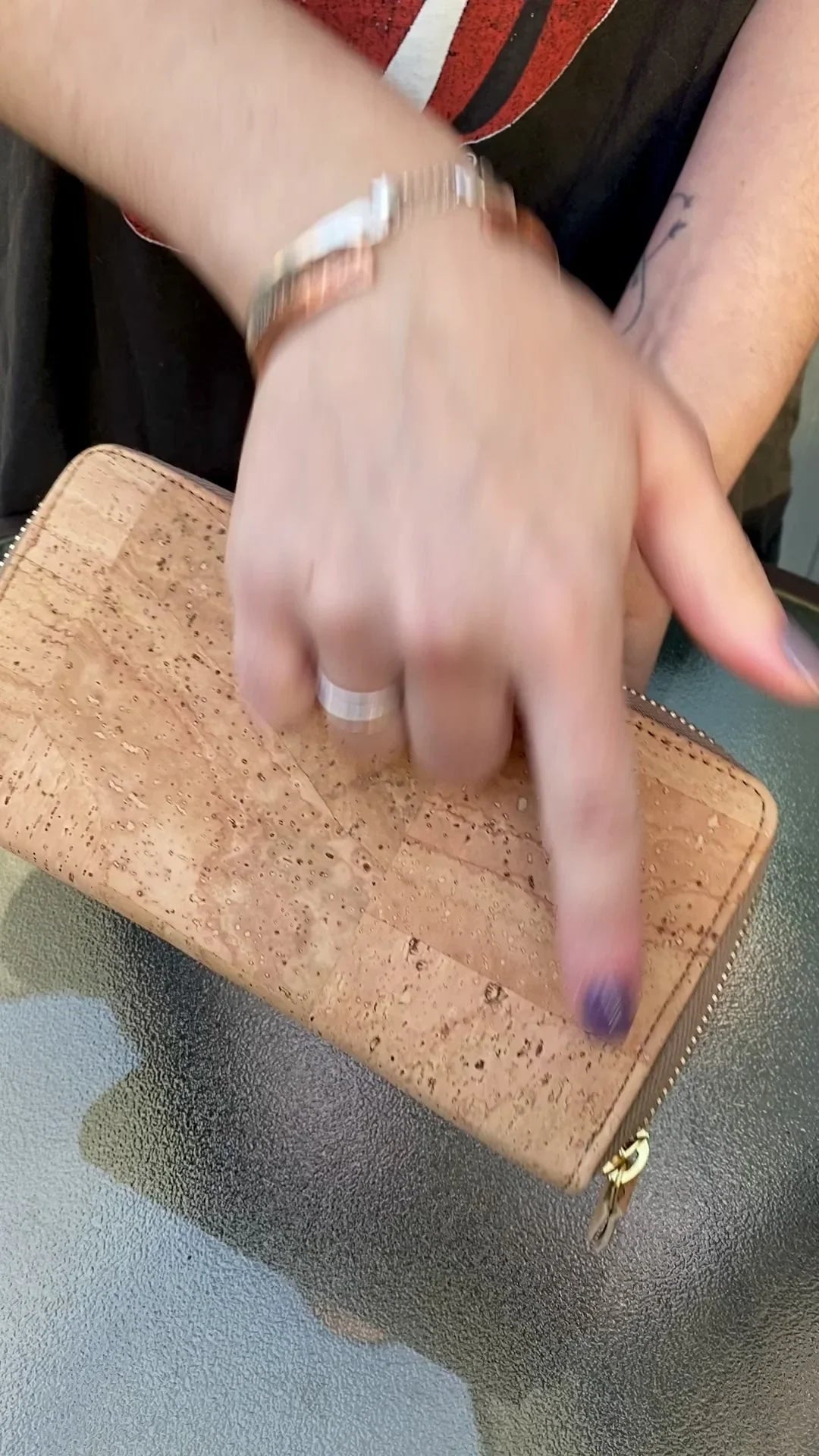 Hand holding a natural cork wallet with gold zipper, eco-friendly accessory at Qu!rk Boutique
