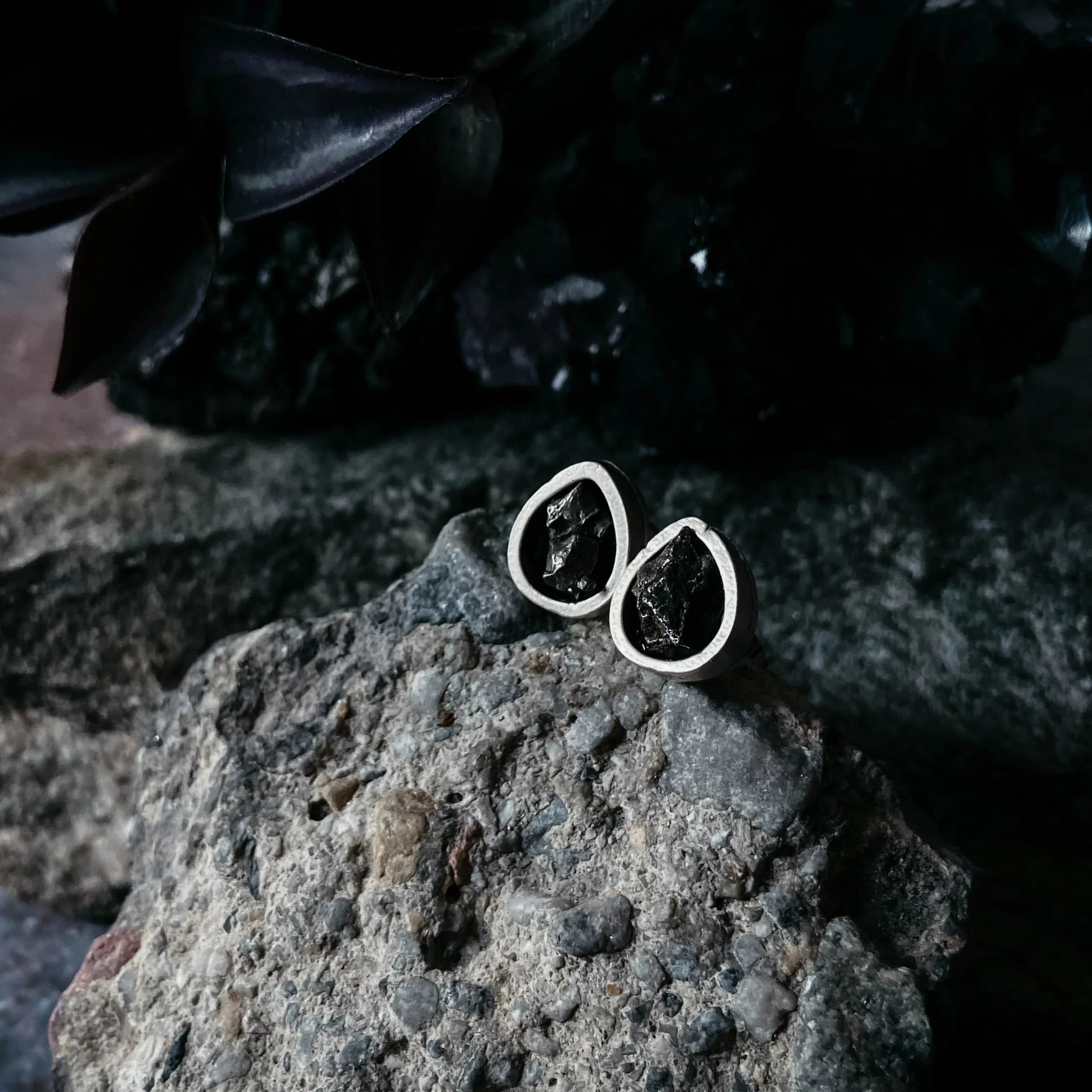 Handmade black stone stud earrings in silver settings on a textured rock, Qu!rk Boutique