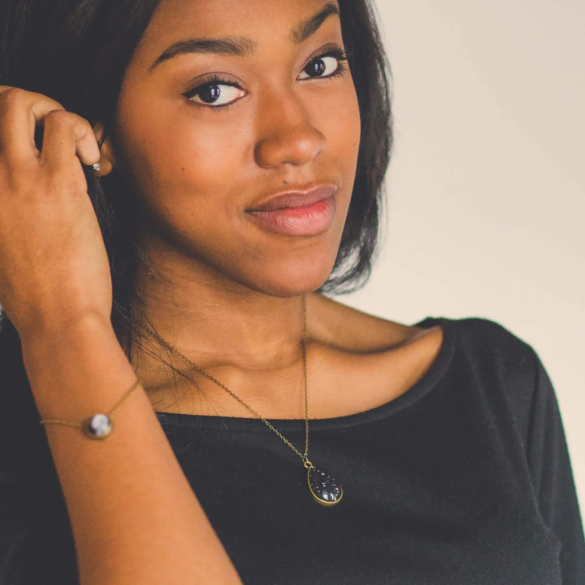 Woman wearing cosmic-inspired necklace and bracelet, Qu!rk Boutique jewelry, black top