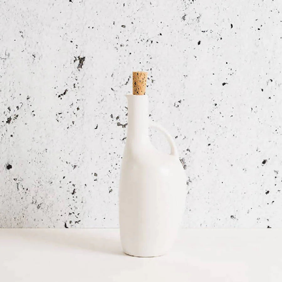 Minimalist white ceramic bottle with cork stopper on speckled background, Qu!rk Boutique style