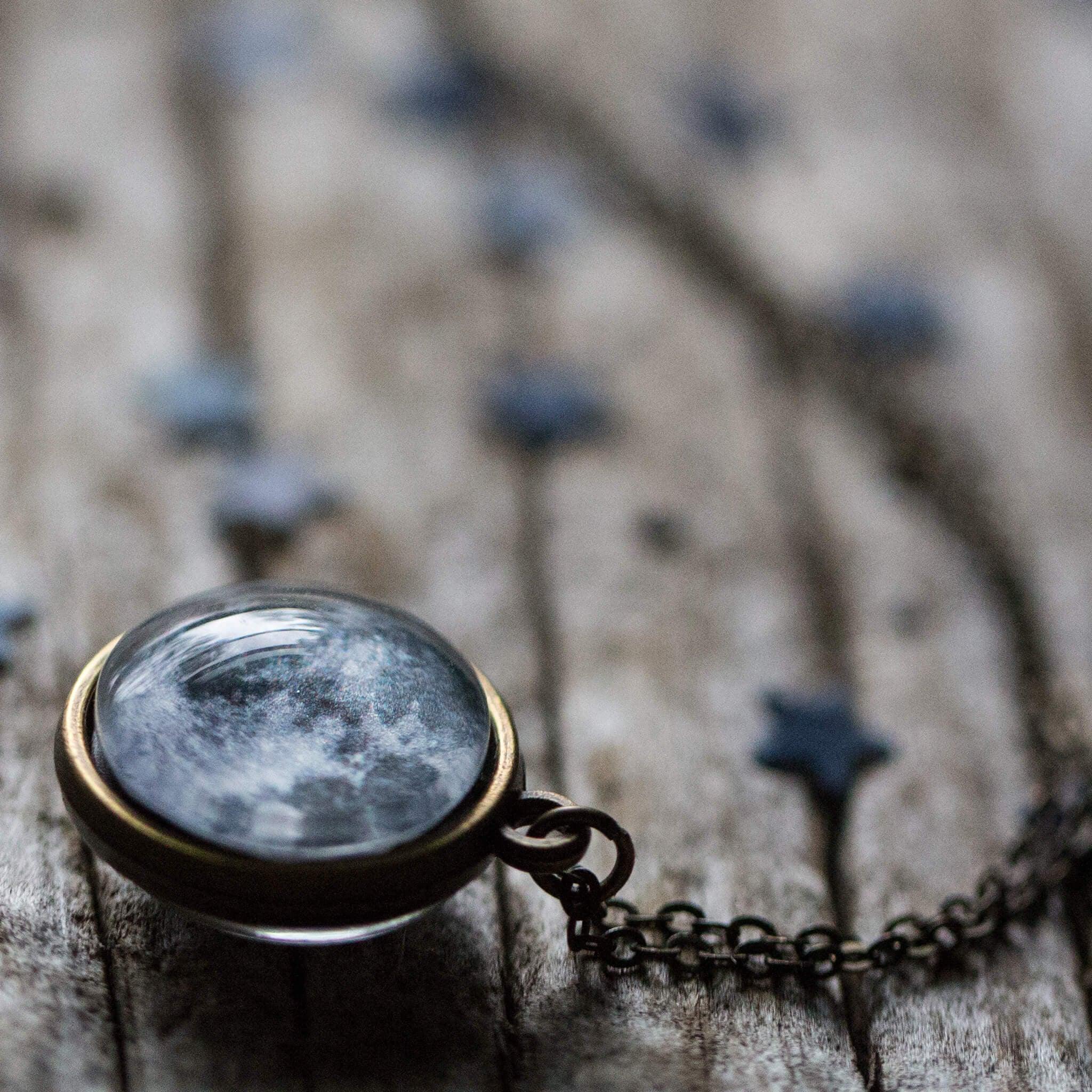 Close-up of a moon pendant necklace on rustic wooden surface with star decorations