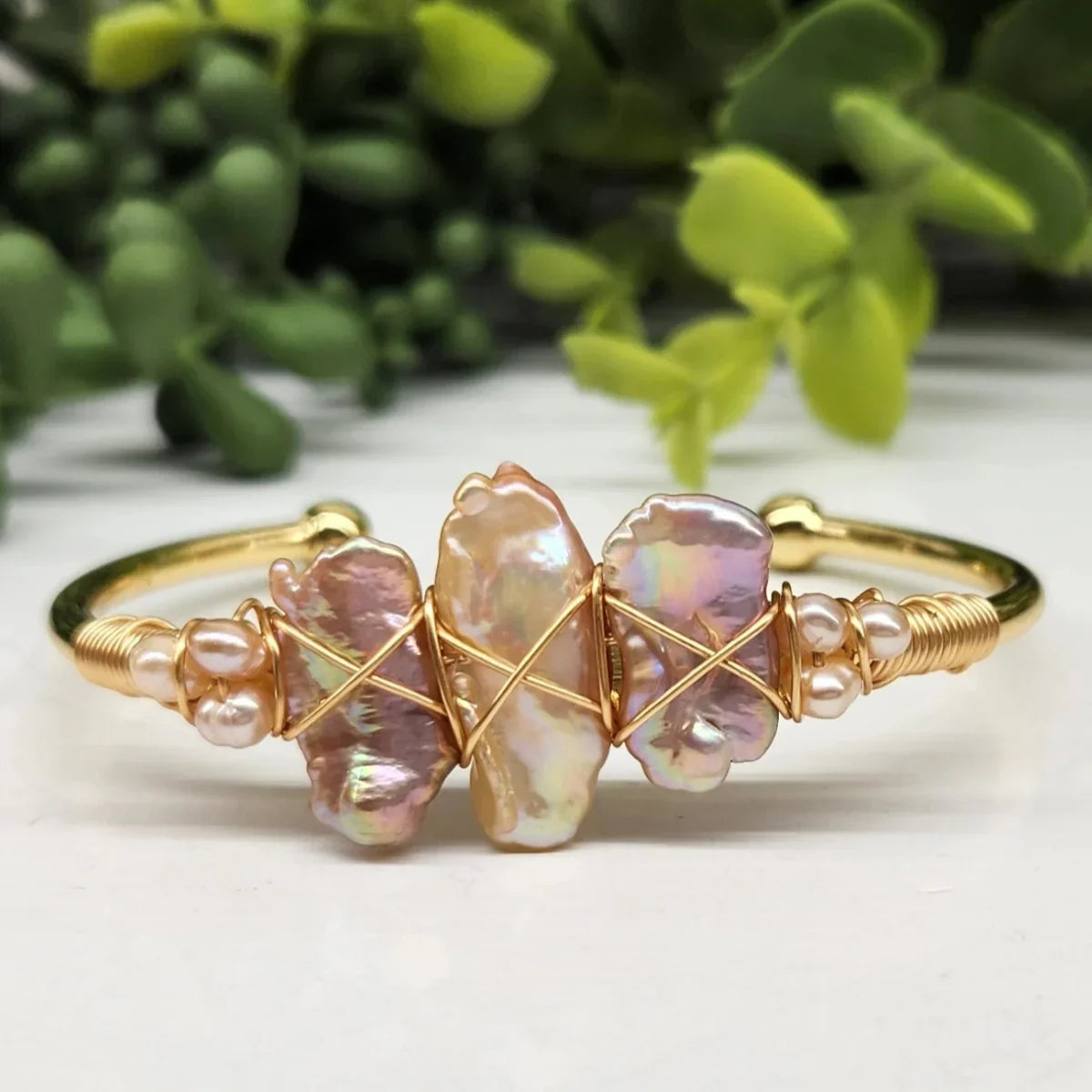 Gold wire-wrapped cuff with iridescent baroque pearls, Qu!rk Boutique jewelry on white surface