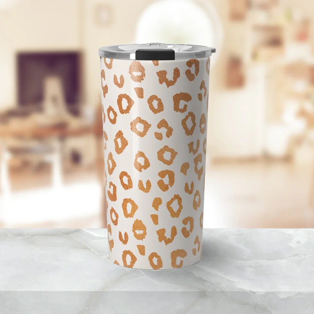 Leopard print insulated tumbler with silver lid on marble countertop in bright kitchen