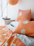 Orange floral duvet cover and matching pillows with white and green accents on white bedding