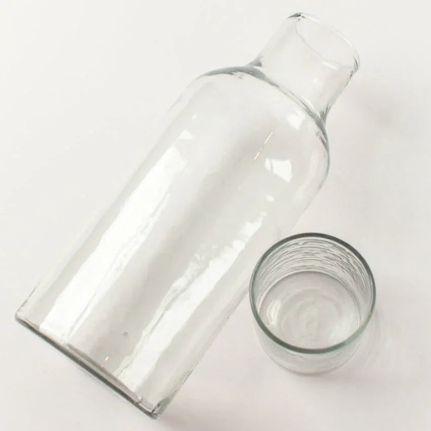 Clear glass carafe and tumbler set on white background, sustainably made from recycled glass