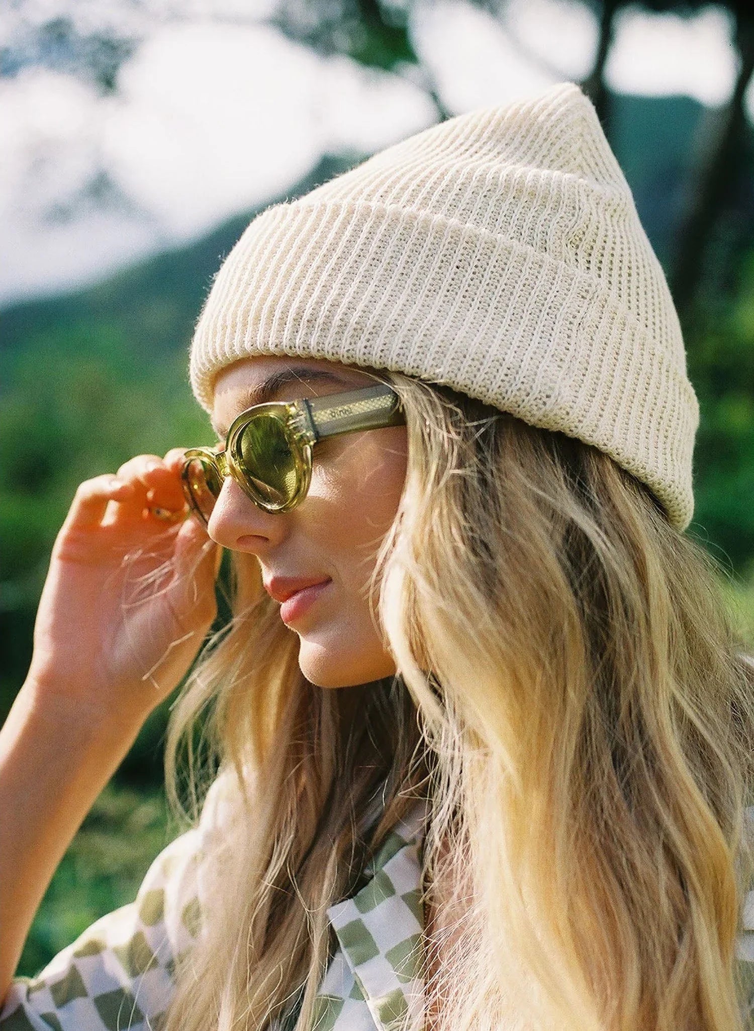 Woman in cream knit beanie and green sunglasses outdoors, Qu!rk Boutique accessory style