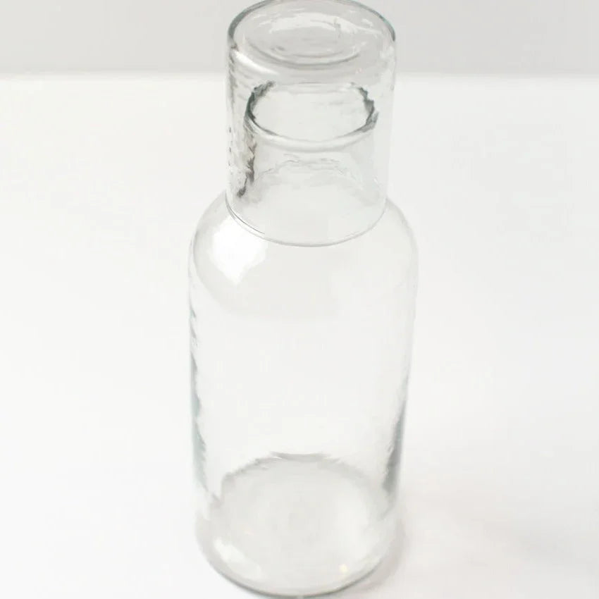 Clear recycled glass bottle on white background, sustainable gift at Qu!rk Boutique