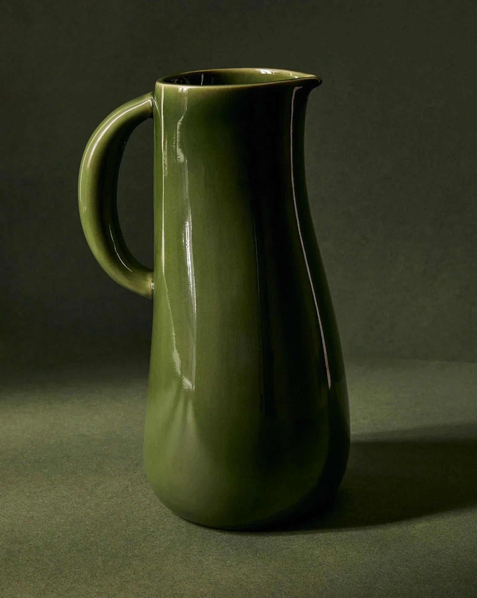 Glossy green ceramic pitcher on dark background, artist-designed home decor from Qu!rk Boutique