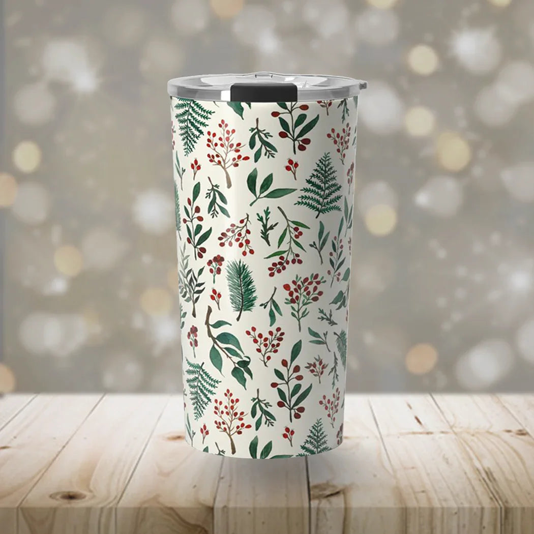 Tumbler with holiday foliage pattern featuring green leaves and red berries on wood surface