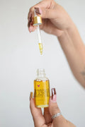 Hand holding dropper above a bottle of BE YOU beauty oil from Qu!rk Boutique