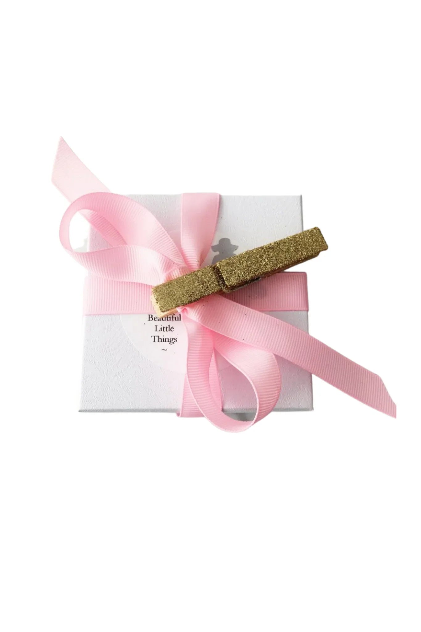 White gift box with textured pattern, wrapped in pink ribbon and gold glitter clothespin
