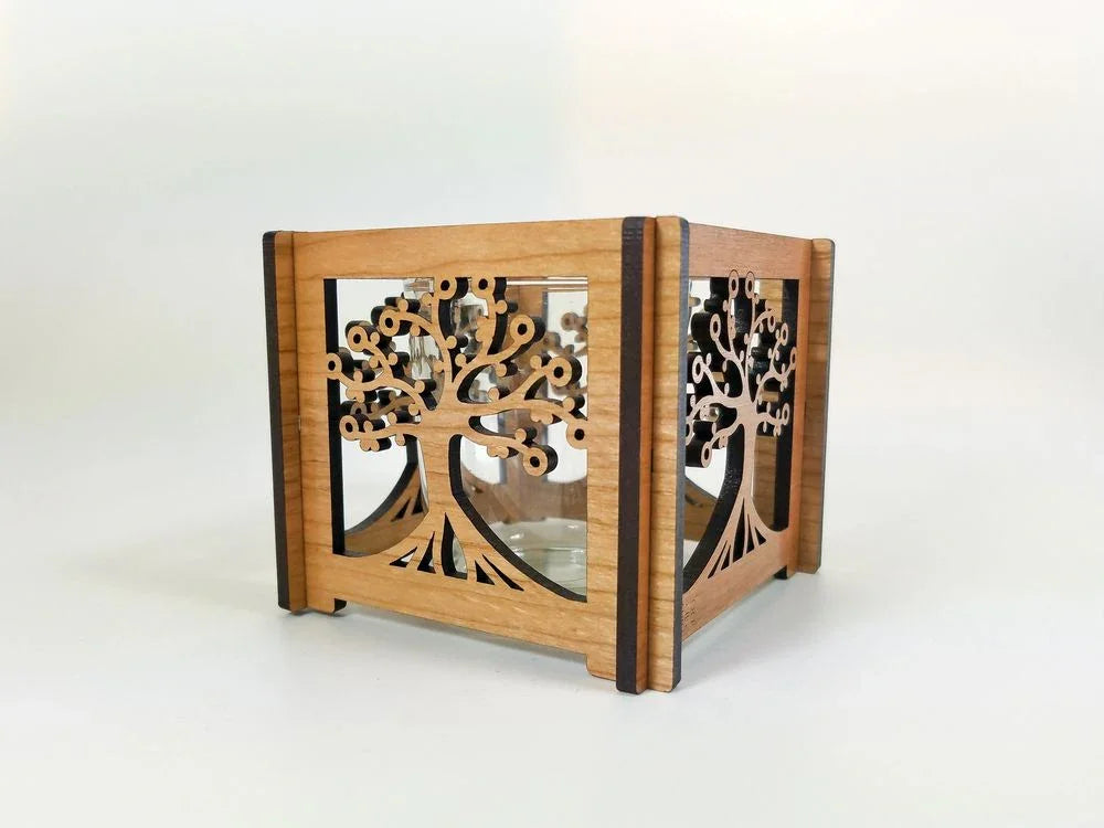 Wooden cube candle holder with intricate tree of life cutout design on a white background