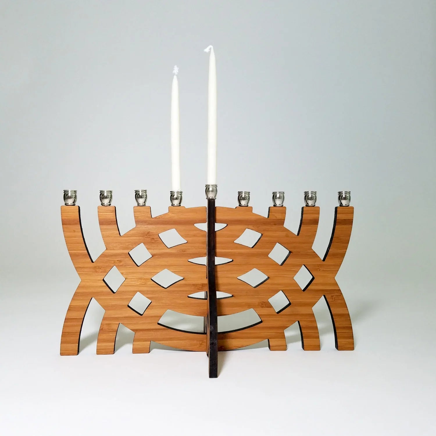 Modern wooden Hanukkah menorah with intersecting arcs design and two white candles