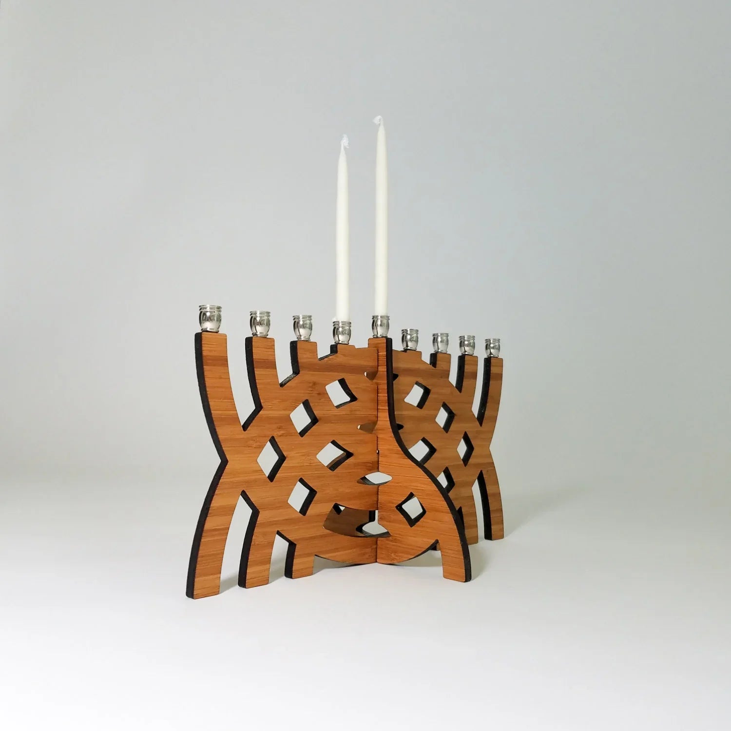 Modern wooden Hanukkah menorah with intersecting arcs design and two white candles