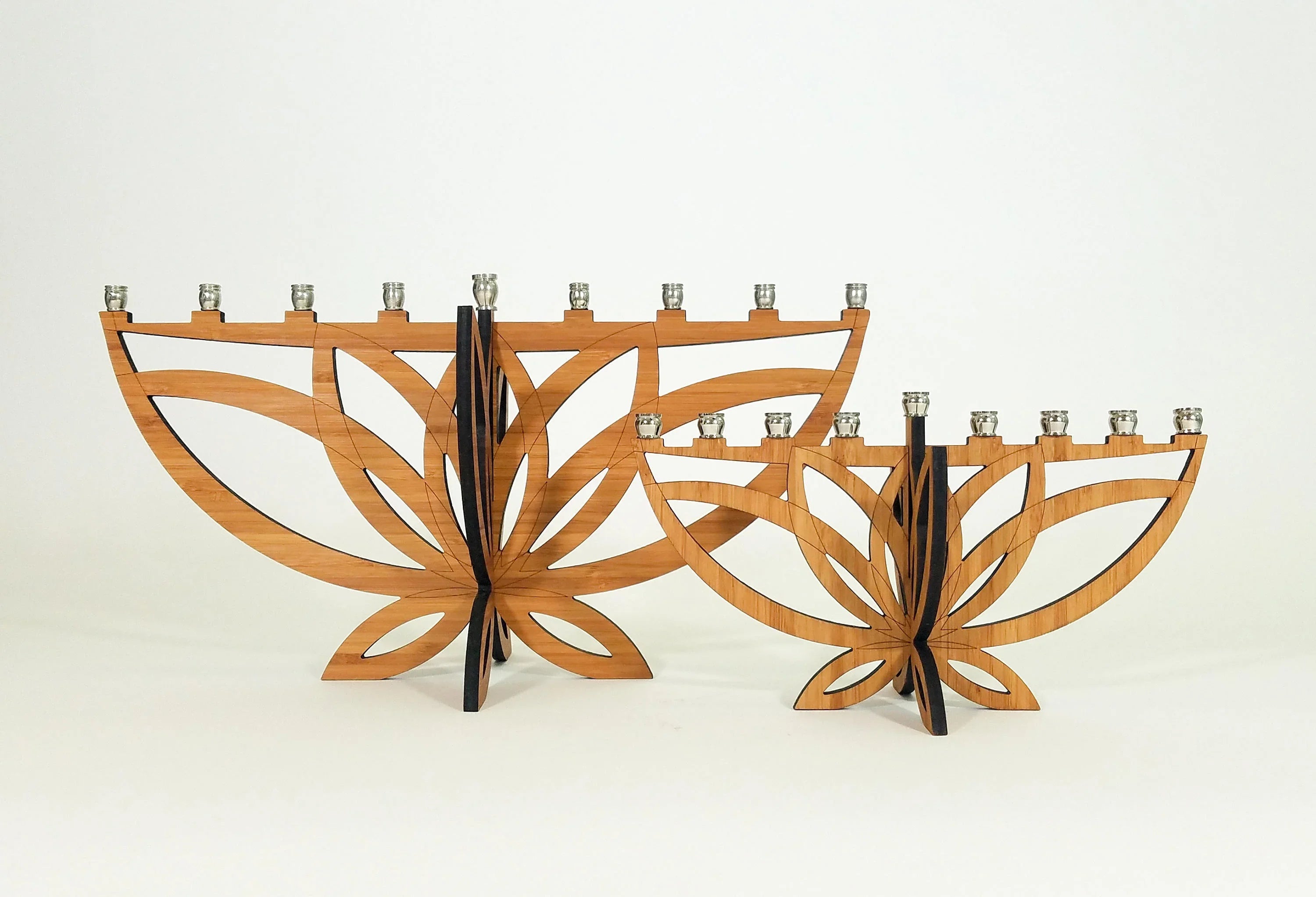 Two wooden menorahs shaped like lotus flowers with metal candle holders on a white background
