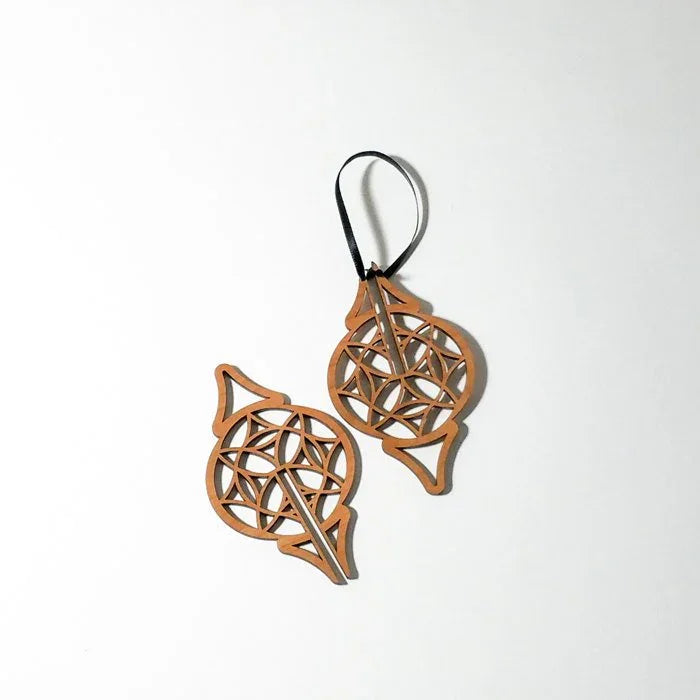 Laser-cut wood Christmas ornaments with geometric patterns on white background