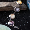 Artist-designed cosmic planet bracelet on black starry background, Qu!rk Boutique jewelry