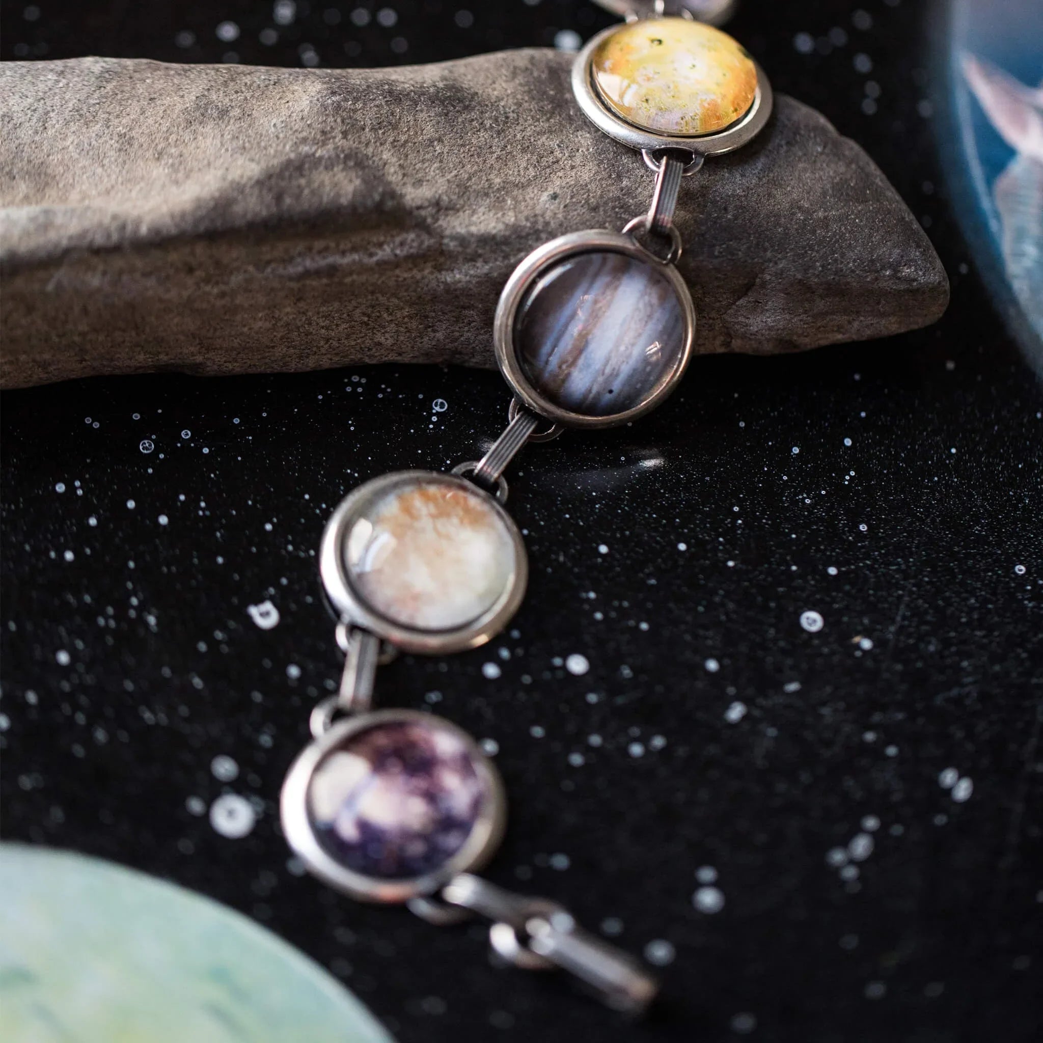 Artist-designed cosmic planet bracelet on black starry background, Qu!rk Boutique jewelry