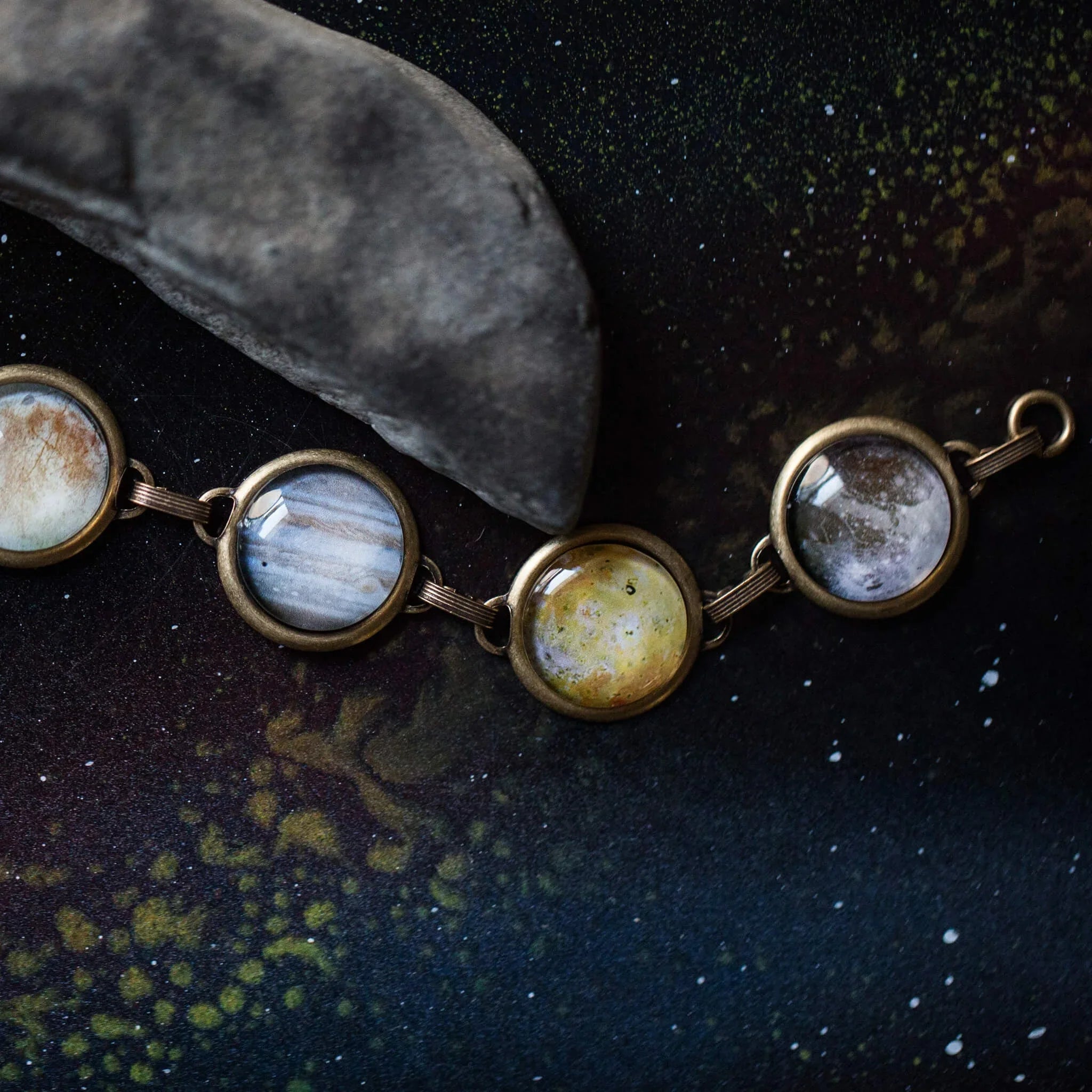 Cosmic planet bracelet with four round charms on a dark starry Qu!rk Boutique background