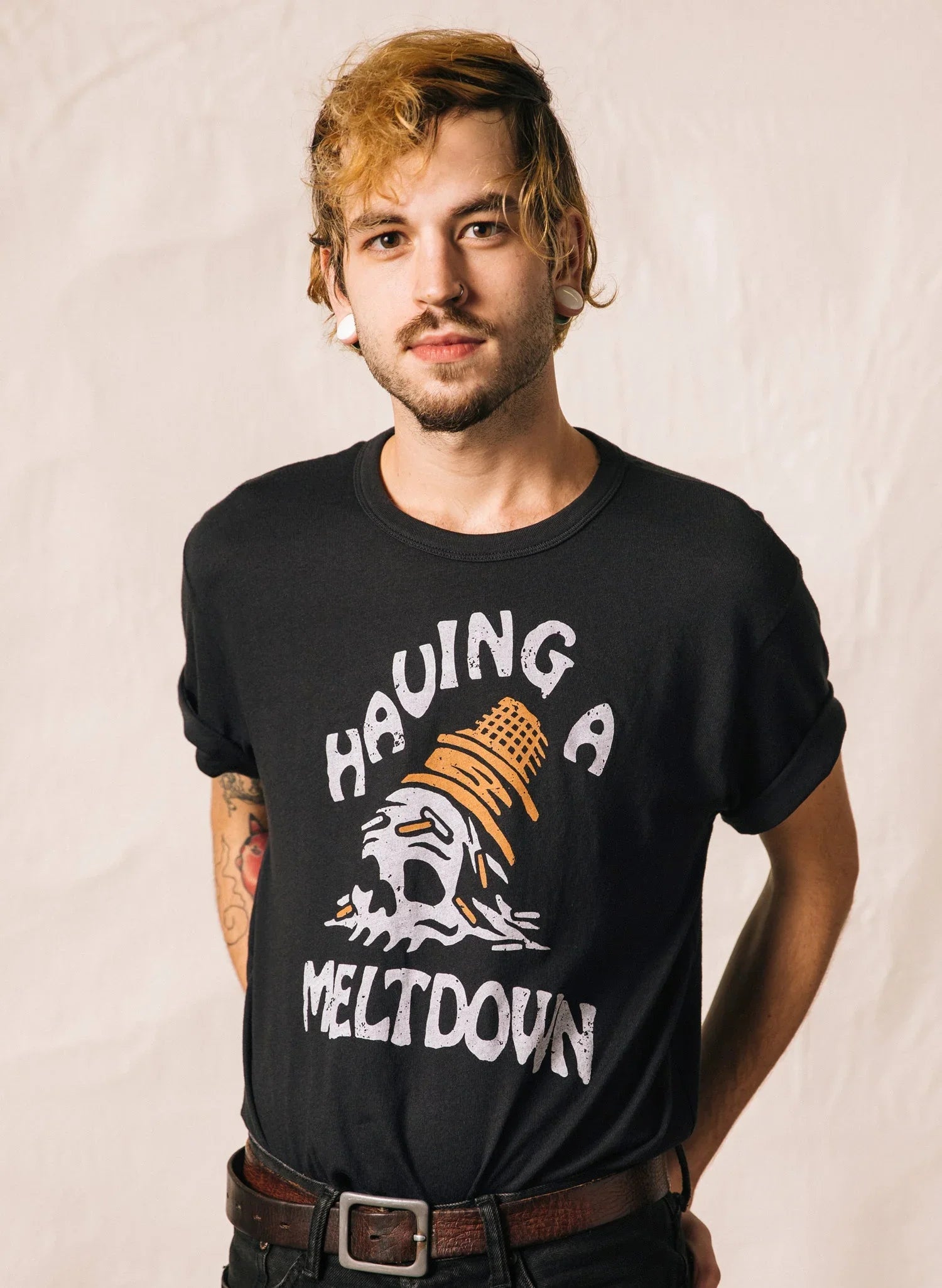 Young man with tattoos wearing black tee featuring melting skull and cone and text Hauling a Meltdown