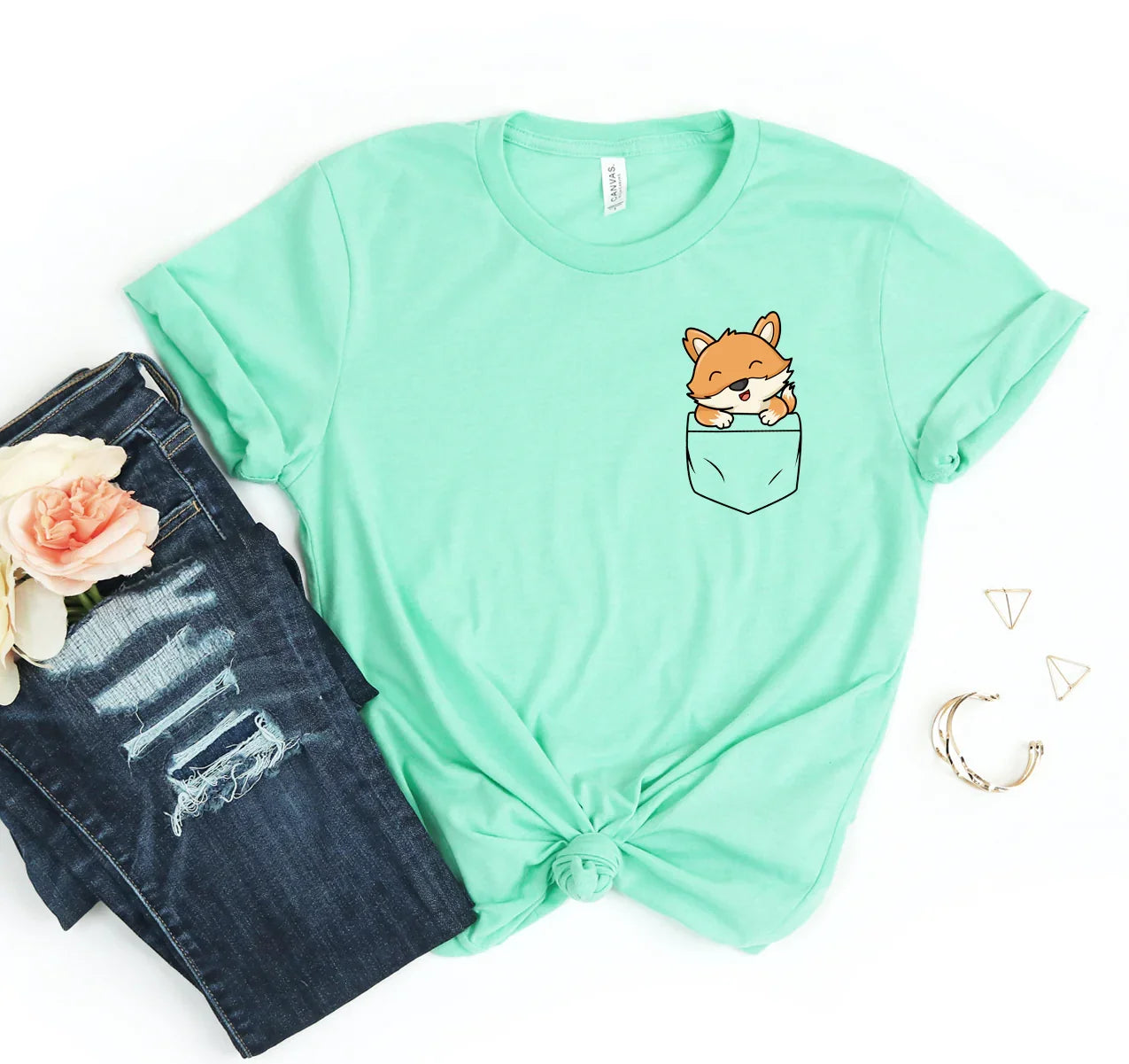 Mint green t-shirt with cute fox graphic in chest pocket, paired with ripped dark blue jeans and floral accent
