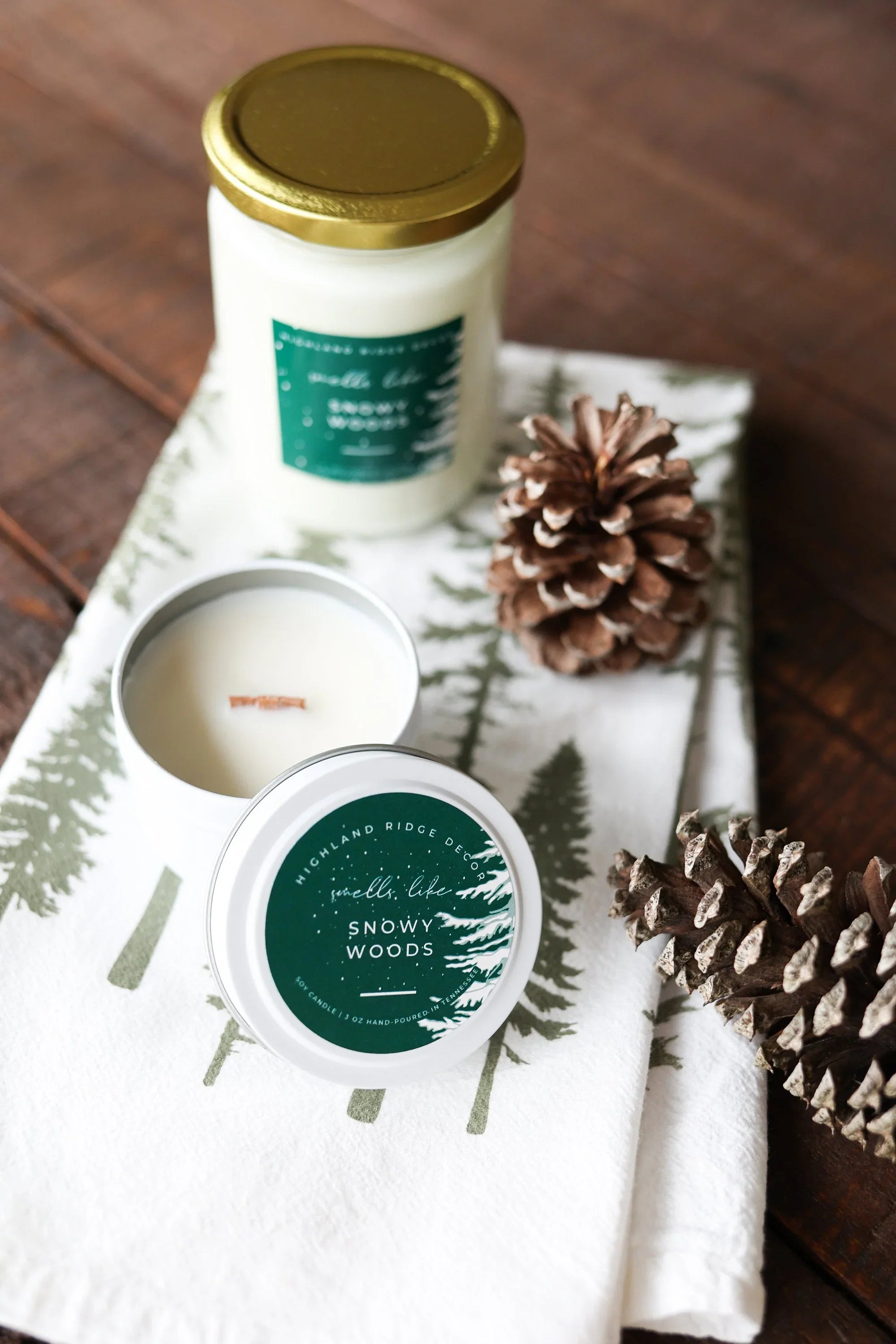 Snowy Woods soy candles on forest print napkin with pine cones, eco gift at Qu!rk Boutique