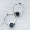 Handmade silver hoop earrings with blue and beige beads on white background, Qu!rk Boutique
