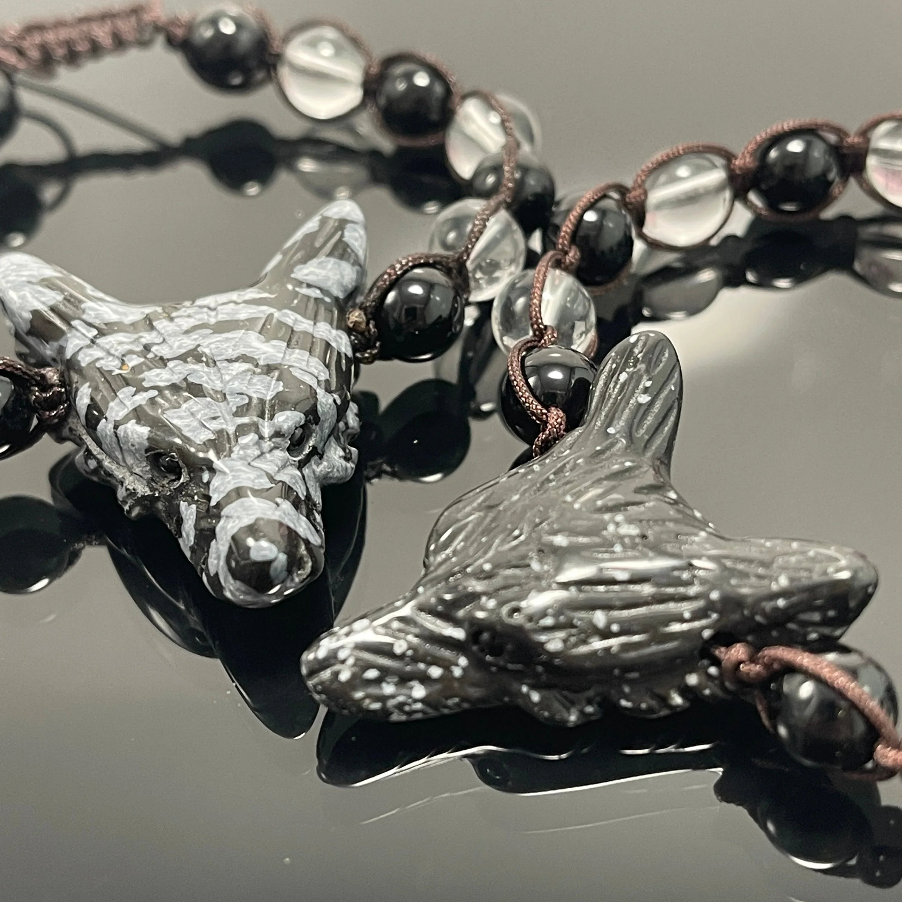 Handcrafted snowflake obsidian wolf head beaded necklace on reflective black background