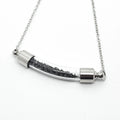 silver chain necklace with curved glass pendant containing black particles