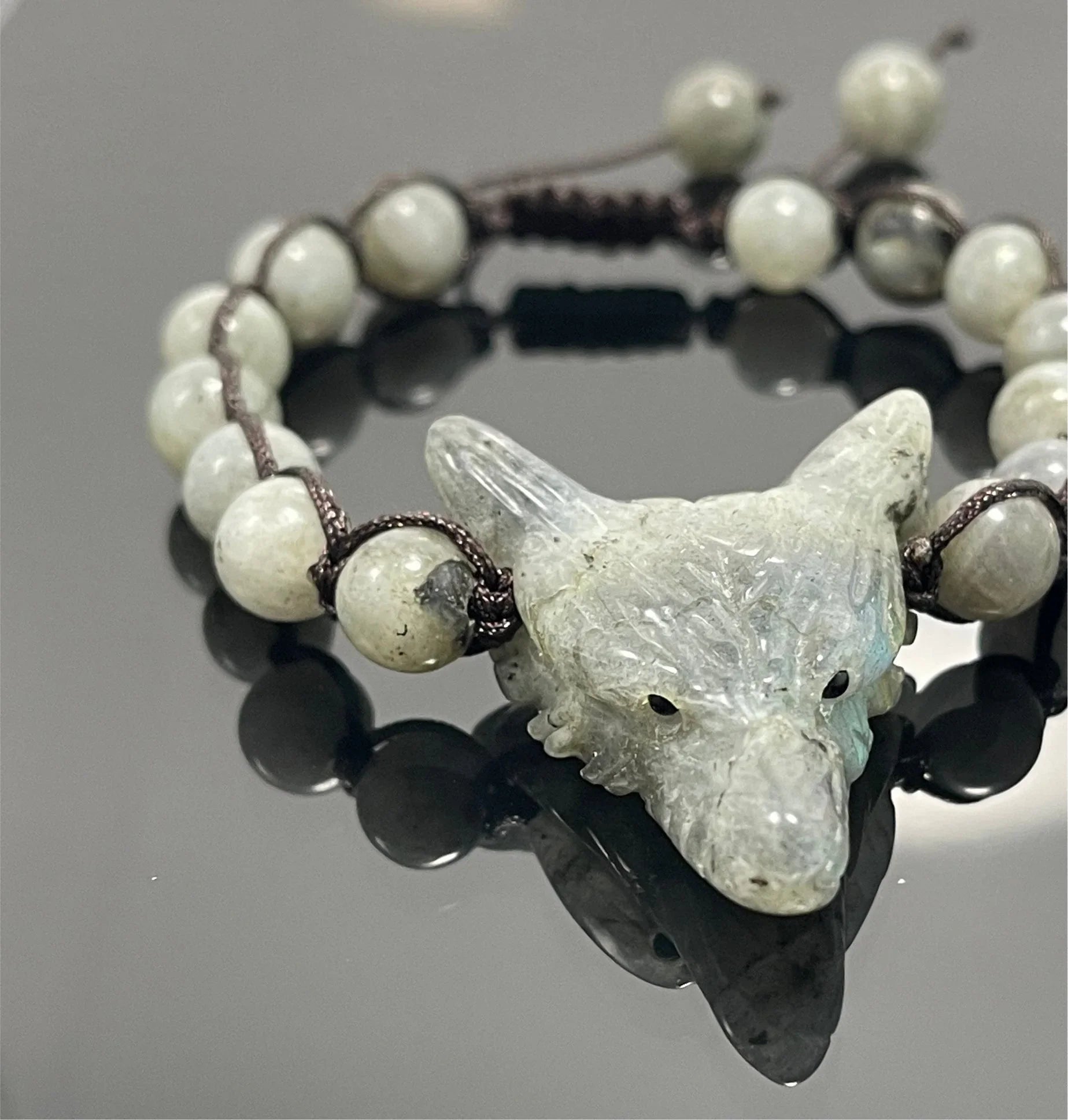 Labradorite wolf head beaded bracelet on black surface, artisan jewelry at Qu!rk Boutique