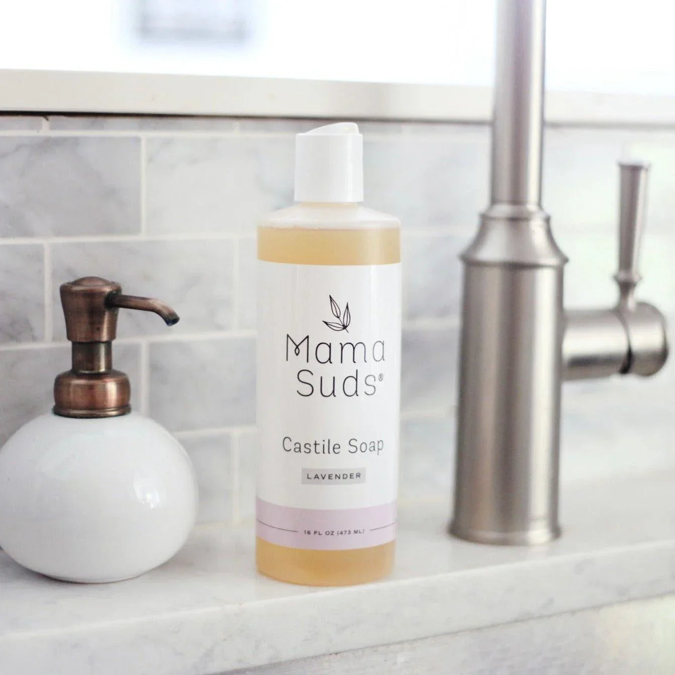 Mama Suds lavender Castile soap bottle on marble countertop near modern metal faucet at Qu!rk Boutique